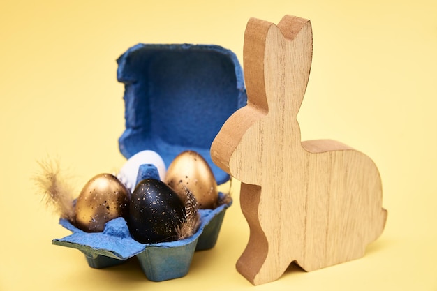 Houten konijn en gekleurde eieren op gele achtergrond Happy Easter card