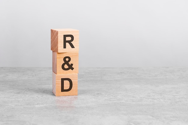Houten kubus op een tafel met tekst R en D kopieerruimte rechts voor ontwerp grijze achtergrond