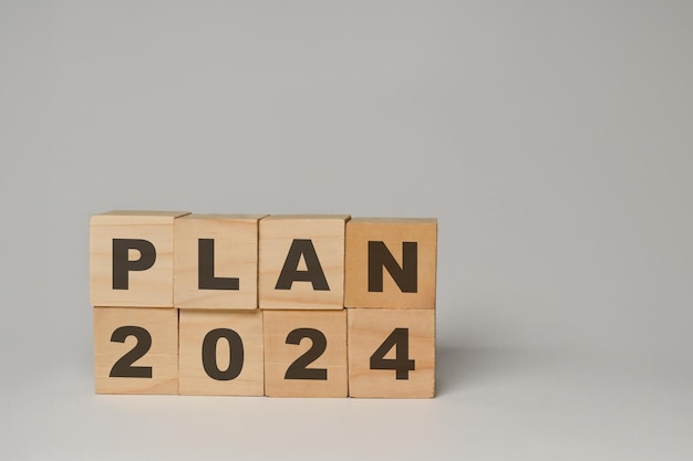 Houten kubusblokken met het woord PLAN 2024 op witte achtergrond Doelstellingen van het bedrijfsactieplan en strategieconcept