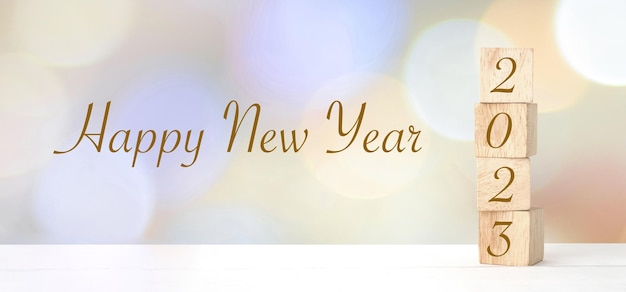 Houten kubussen met 2023 en gelukkig nieuwjaar over de achtergrond wazig bokeh