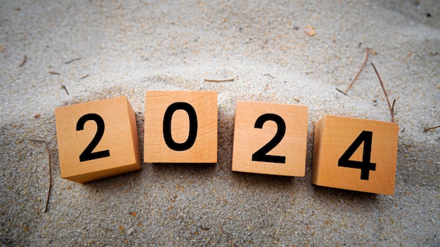 Houten kubussen met 2024 en gelukkig nieuwjaar op de achtergrond van het zand op het strand