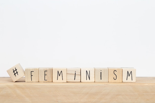 Foto houten kubussen met een hashtag en het woord feminisme, sociale media concept