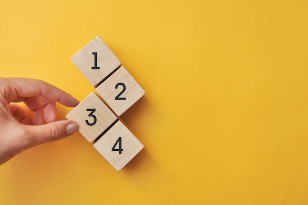Foto houten kubussen met nummers van één tot vier, prioriteitsselectie op een gele achtergrond