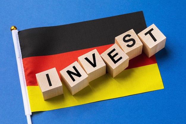 Houten kubussen met tekst en een vlag op een gekleurde achtergrond het concept van investeringen uit Duitsland
