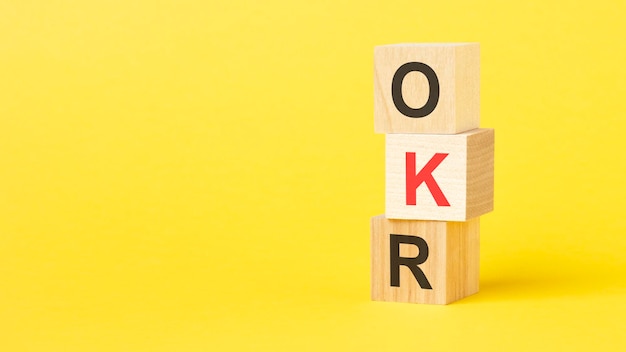 houten kubussen met tekst OKR gele achtergrond