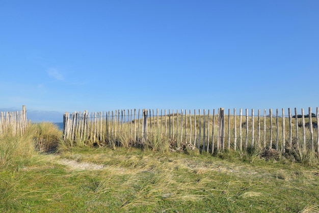 Houten kustomheining in het duin voor blauwe zee en lucht in Bretagne, Frankrijk