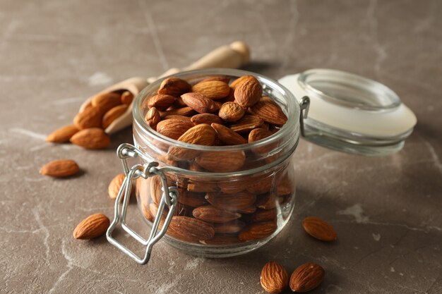 Houten lepel en glazen pot met amandel op grijze tafel. vitamine voedsel