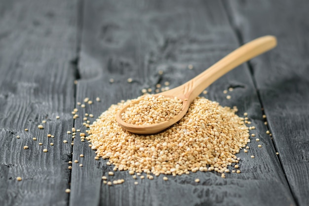 Houten lepel in een stapel van quinoa zaden op een donkere houten tafel