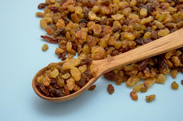 Houten lepel met rozijnen op een blauwe culinaire achtergrond als achtergrond