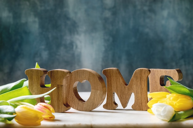 Houten letters THUIS op een tafel met tulpenbloemen