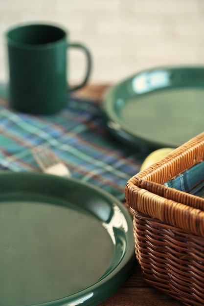 Houten mand voor picknick met borden, kopjes en bestek van dichtbij