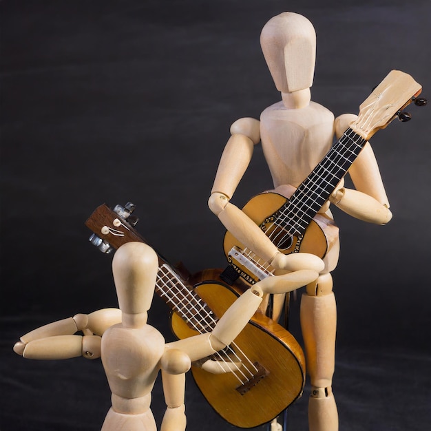 Foto houten mannequinfiguren met een gitaar op een zwarte achtergrond
