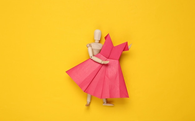 Houten marionet met Origami papier rode jurk op gele achtergrond
