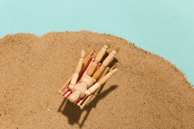 Houten marionet zonnebaadt op de ligstoel op zand op een zonnige dag. Strandvakantie Concept. Zomerrust