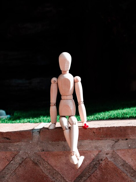 Houten menselijke figuur zittend op stap naast tuin