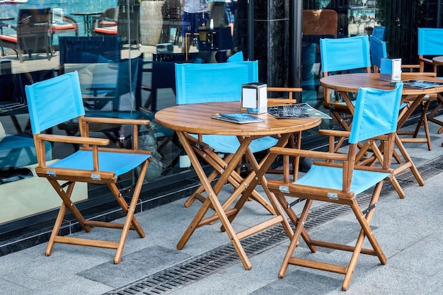 Houten meubels met kleurstof voor gasten in de buurt van glazen gevel van café op straat in de stad