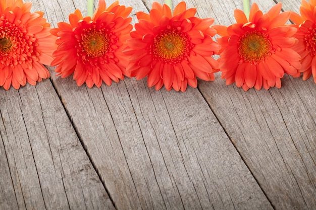 Houten ondergrond met oranje gerbera bloemen