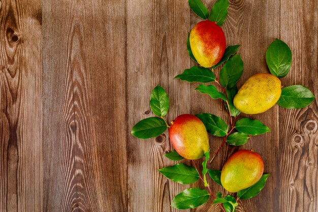 Houten oppervlak met mango en groene bladeren