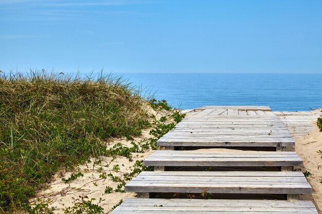 Houten pad in de duinen met toegang tot de zee. Zomerweekend aan zee