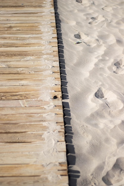 Houten pad naar het strand omgeven door goudkleurig zand