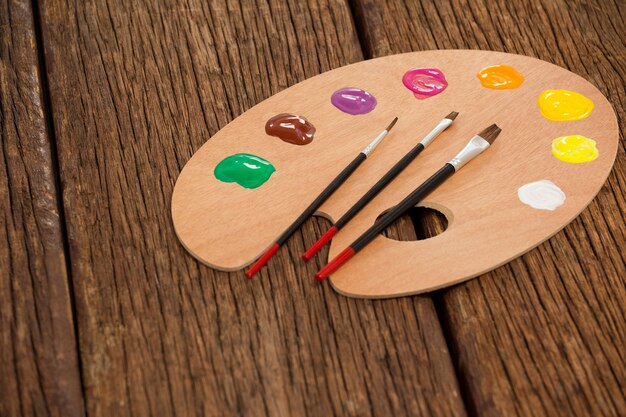 Foto houten palet met meerdere kleuren en penselen op houten tafel