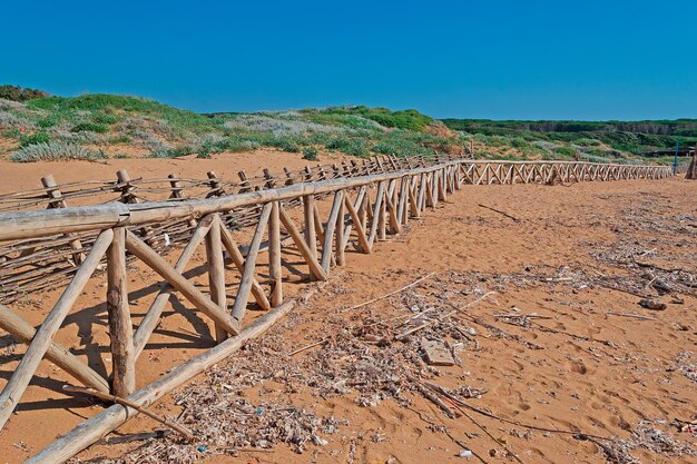 Houten palissade op een rommelig strand