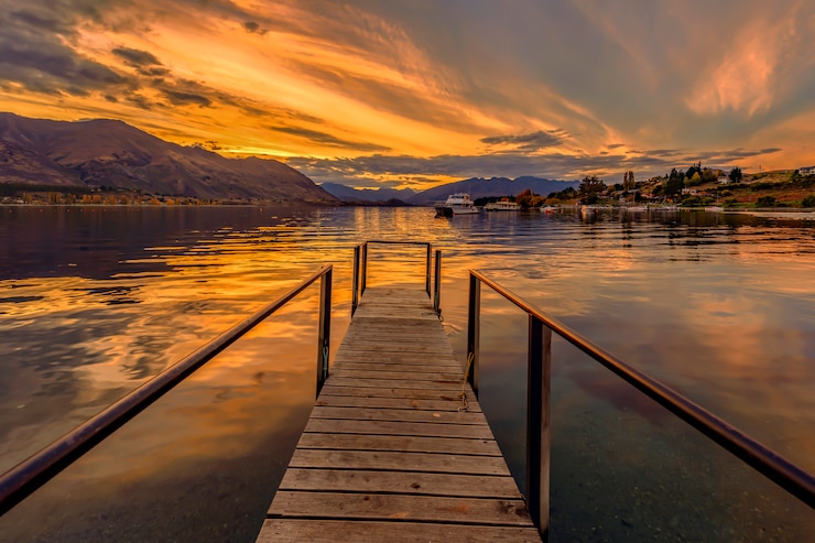 Foto houten pier die leidt naar een rustig meer bij zonsondergang