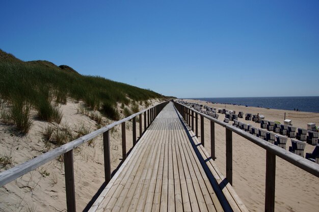 Houten pier op verlaten strand met blauwe wolkenloze lucht