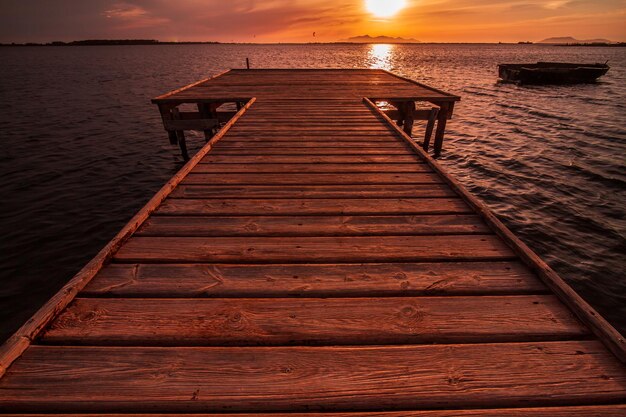 Foto houten pier over de zee tegen de dramatische hemel bij zonsondergang