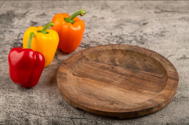 Houten plaat van kleurrijke zoete paprika op stenen oppervlak