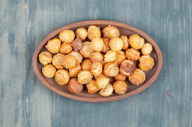 Houten plaat van ronde crackers met sesamzaadjes op houten oppervlak.