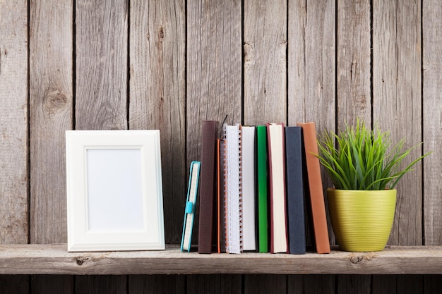 Houten plank met fotolijsten boeken en plant