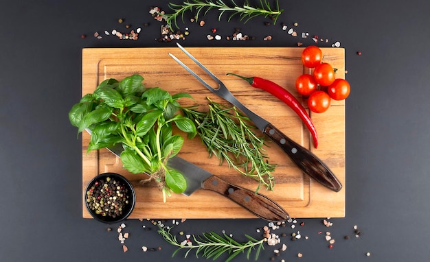 Houten plank met rozemarijnkruiden en mes en vork voor vlees