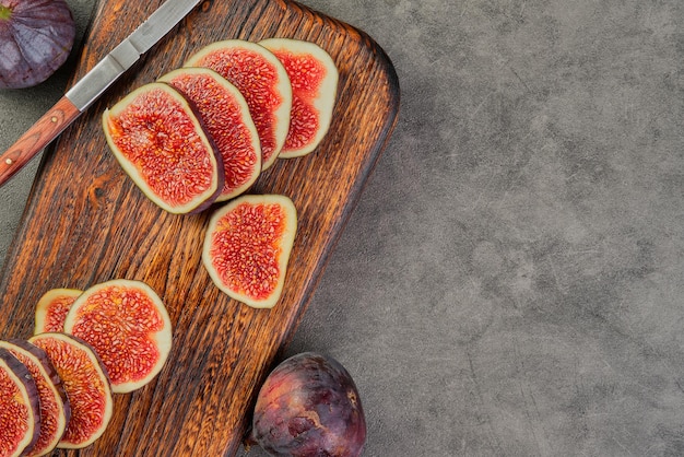 Houten plank met verse vijgen in plakjes gesneden en een oud mes op een grijze keukentafel met kopieerruimte seizoensgebonden rijp fruit mediterraan dieet