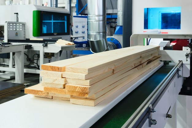 Houten planken op een houtbewerkingsmachine in een moderne meubelfabriek