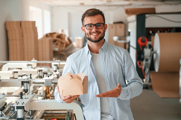 Houten platen vasthouden en laten zien drukkerijmedewerker in witte kleren is binnen