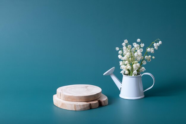 Houten podium of sokkel met lelietje-van-dalenboeket in een gieter op een turkooizen achtergrond