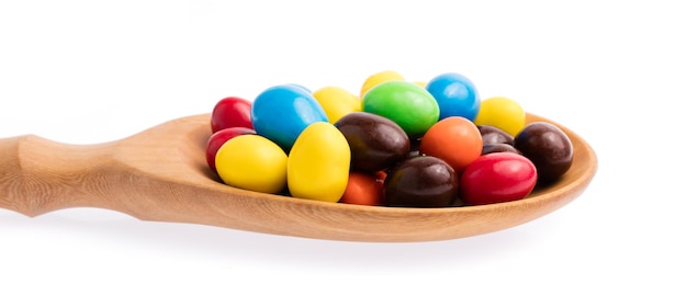 houten pollepel van kleurrijke chocolade snoepjes knoppen geïsoleerd op een witte achtergrond