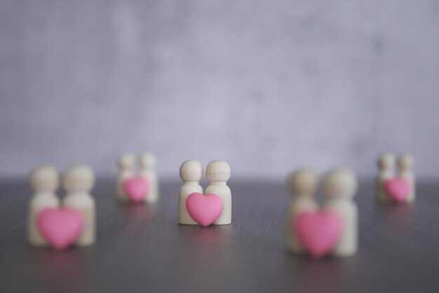 Houten poppen en een roze hart met kopieerruimte Liefde romantische relatie koppel concept