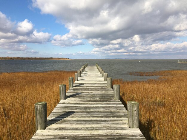 Foto houten promenade die naar het water leidt tegen de lucht