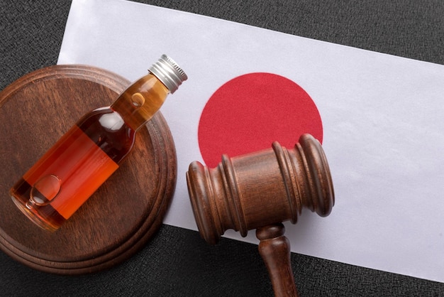 Houten rechter en fles met alcohol op de vlagachtergrond van Japan Alcoholwet in Japan