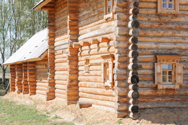 Houten rustiek huis gemaakt van hout en ramen met gebeeldhouwde luiken in de oude Russische plattelandsstijl. bouw van huizen gemaakt van natuurlijke ecologische materialen