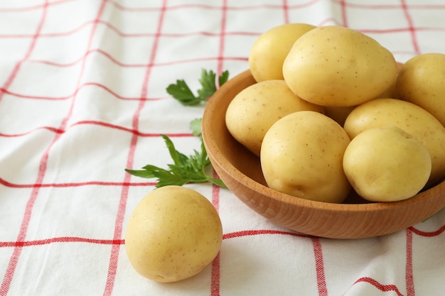 Houten schaal met jonge aardappel op tafelkleed