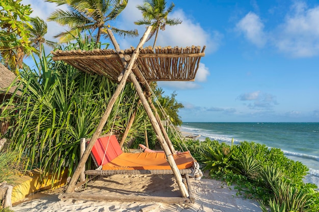 Houten schommel onder een baldakijn op het tropische strand bij het zee-eiland zanzibar tanzania oost-afrika