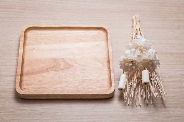 Houten schotel met gedroogde bloem op de houten achtergrond.