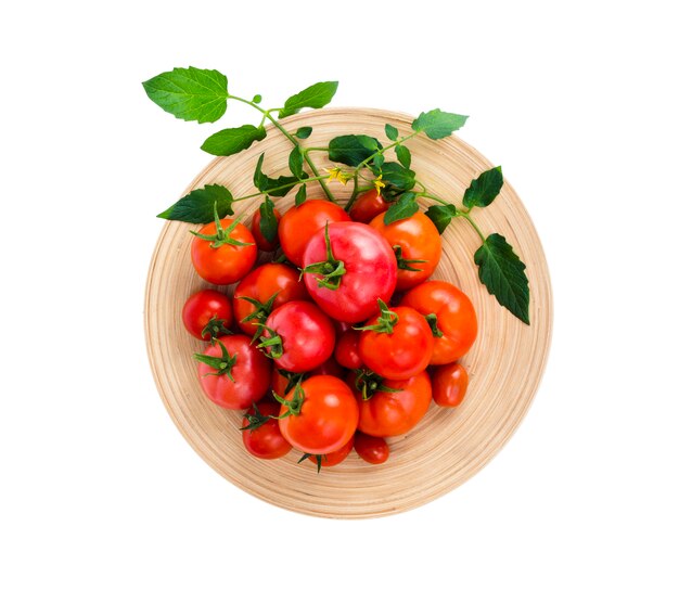 Houten schotel met verschillende rijpe tomaten op witte achtergrond.