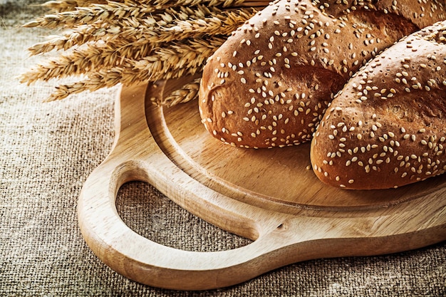 Houten snijplank brood tarwe oren op plundering achtergrond