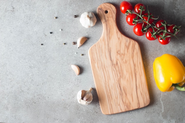 Houten snijplank met verse kruiden en rauwe groenten op rustieke houten tafel. Bovenaanzicht. Koken achtergrond.