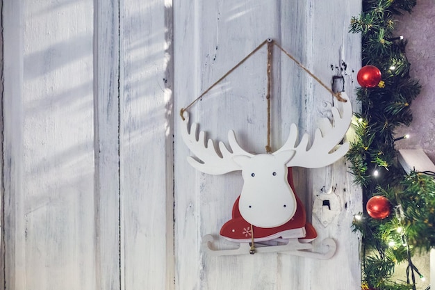 Houten speelgoed eland-elandschaatsen in een kerstmankostuum hangend aan een muur omringd door dennentakken