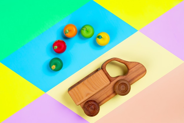 houten speelgoed vrachtwagens met appels op een geïsoleerde veelkleurige levendige geometrische achtergrond.